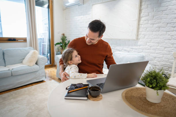 istock Daughter makes a company to her father, while he working on laptop from home 1962351407