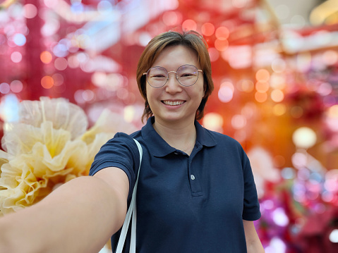 An Asian woman is enjoying selfie with Chinese New Year decorations in shopping mall
