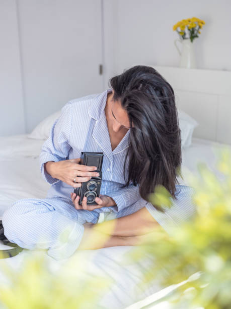 istock Female with vintage photo camera sitting on bed 1962368775