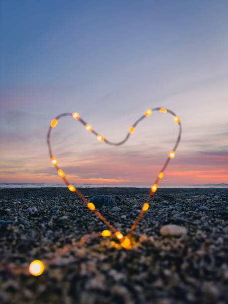istock heart symbol with bright fairy lights on the beach 1962384947