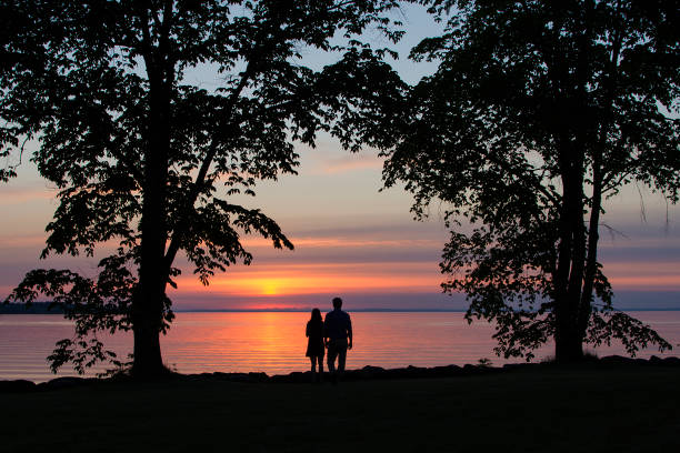 Silhouettes of unrecognizable man and woman watching the sunset.