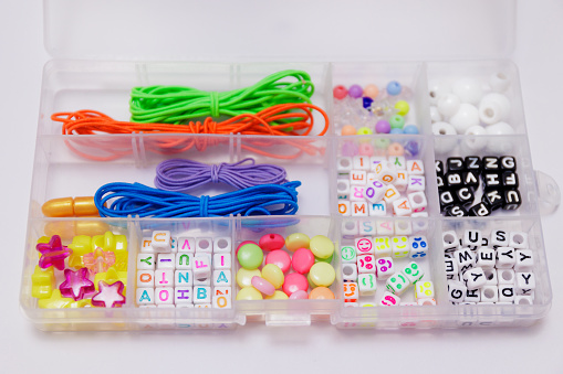 Box with multi-colored beads and elastic band for bracelet on white background