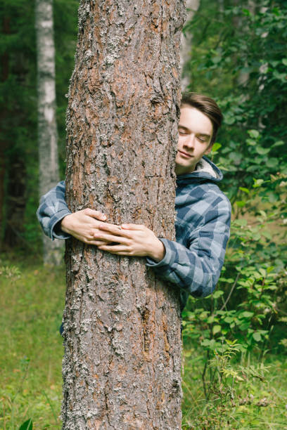 istock Teen boy hugs pine tree in a forest 1962414950