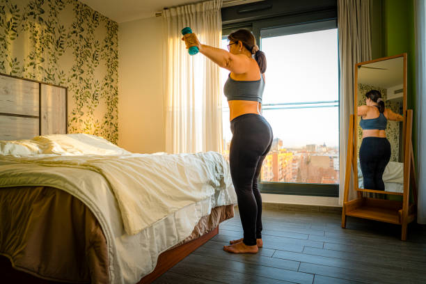 istock Mature woman with dumbbells doing exercise in bedroom 1962439063