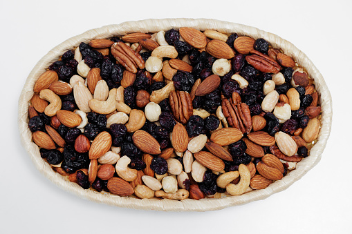 mix of various nuts in wooden bowl over white table background
