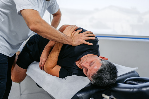 Chiropractor adjusting (cracking) his male client's lower back in his office.