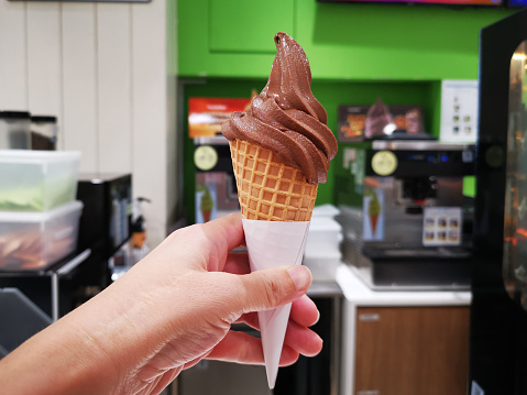 Point of view: Human hand is holding chocolate cone ice cream