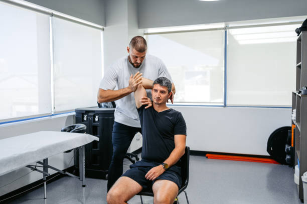 Physical Therapist Adjusting His Male Client's Arm In His Office