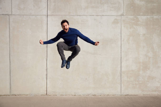 istock Joyful, ecstatic adult man jumping agains concrete wall 1962486642