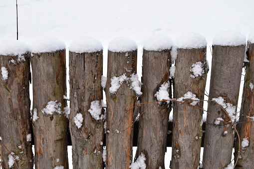 Full frame outdoor morning image of an snow covered weathered wooden fence while snowing in Germany