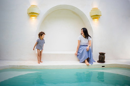 Chinese woman sitting by the pool with her son