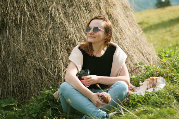 A beautiful woman is resting in the hayloft on a bright, hot, sunny day in the last month of summer.