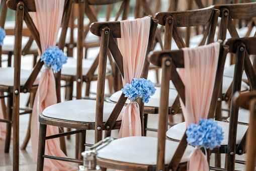 Beautiful wedding venue seats with blue flowers and sashes for ceremony