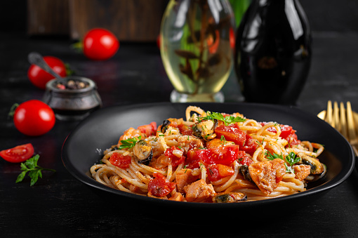 Classic italian pasta spaghetti marinara with mussels and salmon on dark table. Spaghetti pasta with sauce marinara.