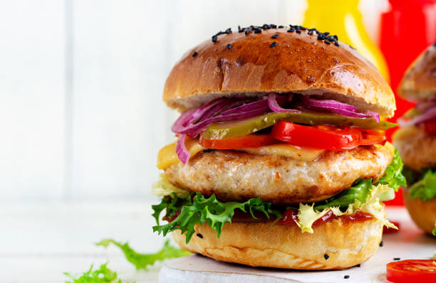 istock Chicken hamburger. Sandwich with chicken burger, tomatoes, cheese, pickled cucumber and lettuce. Cheeseburger. 1962537904