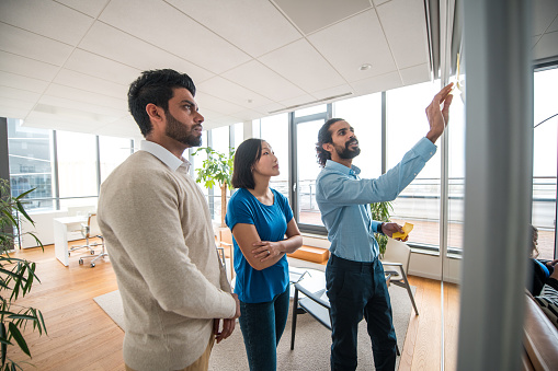 A compact gathering of young colleagues from diverse backgrounds engages in a creative brainstorming session within a corporate work environment. Animated discussions unfold as they explore innovative business strategies.