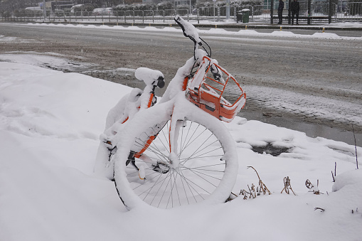 Close up view of a bicycle covered with snow abandoned on a sidewalk in the winter.