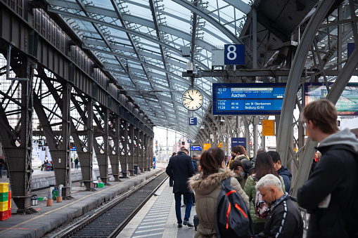 Picture of people waiting for trains in Koln Hbf in Cologne, Germany. Köln Hauptbahnhof or Cologne Central Station is a railway station in Cologne, Germany. The station is an important local, national and international transport hub, with many ICE, Thalys and Intercity trains calling there, as well as regional Regional-Express, RegionalBahn and local S-Bahn trains.