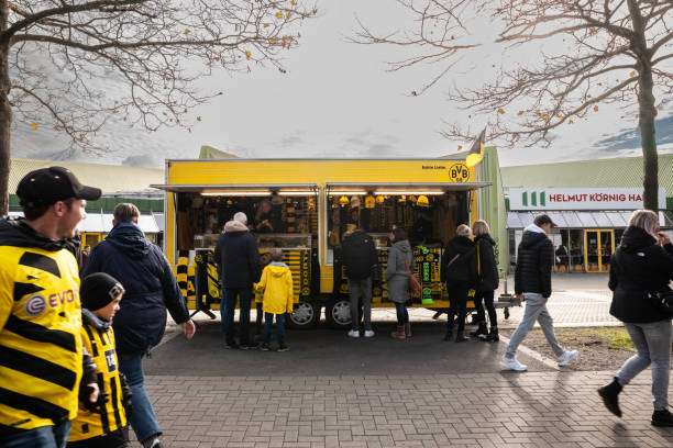 selective blur on bvb borussia dortmund supporters in front of a borussia dortmund fan cart with the football club logo. - borussia dortmund ストックフォトと画像