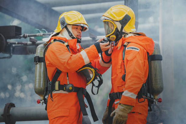 istock Fireman in a helmet takes action, using a water hose to combat a fire in an industrial setting, ensuring safety and protection 1962580609