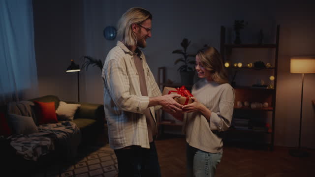 Male presenting gift box to female in evening atmosphere