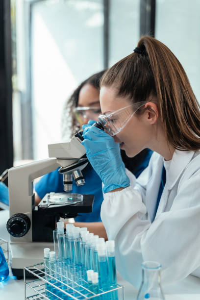 istock Team of biochemical research scientists working with a microscope for vaccine development in pharmaceutical research labeling. 1962598382