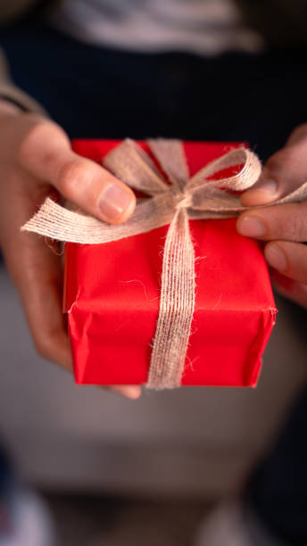 istock Vertical close-up Man's hands opening a Valentine's gift with a bow. 1962604231