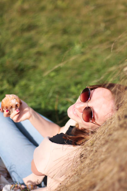a girl in dark glasses drinks coffee with a muffin