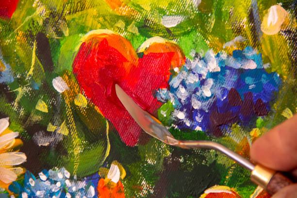 hand of artist with palette knife close-up paints beautiful oil painting of red heart and flowers on canvas. card for wedding and valentine day. - palette knife painting 뉴스 사진 이미지