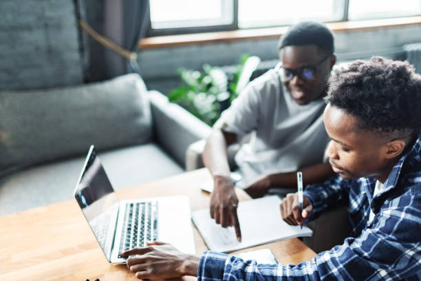 istock Two young adult black male students doing homework using laptop 1962637823