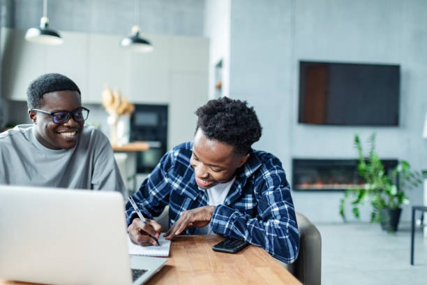 istock Two young adult black male students doing homework using laptop 1962638541
