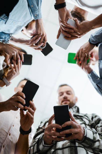 istock Low Angle Of Business Team Members Using Smartphones 1962647309