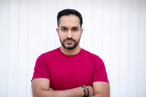 Relaxed portrait of a handsome mid-adult male. He is wearing a red t-shirt and has his arms crossed.