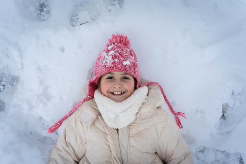 Stock photo of one little girl who is running in the snow. She is having fun. She is looking at camera and move towards it. Plenty of copy space on the right.