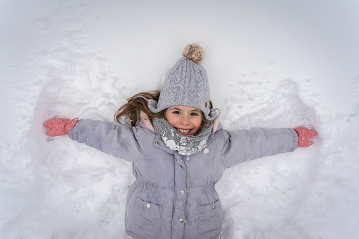 High angle view of an playful Caucasian girl making an snow angel