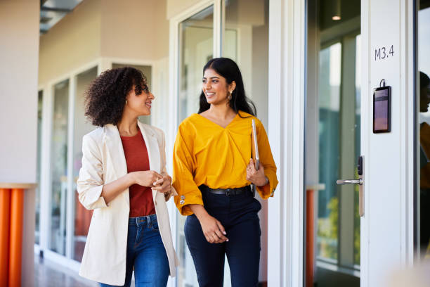 istock Young businesswomen talking and smiling while walking down an office corridor 1962648387