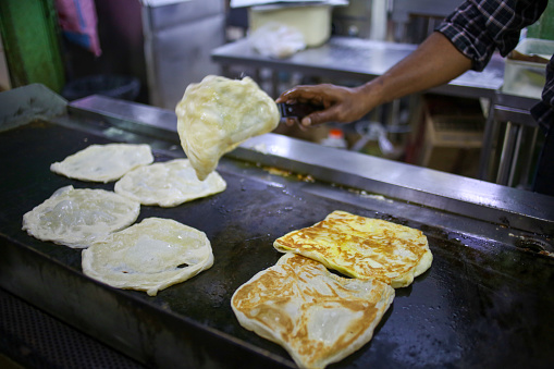 Portrait shot of an asian man making roti canai