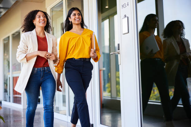 istock Two diverse businesswomen smiling while walking in an office hallway 1962648454