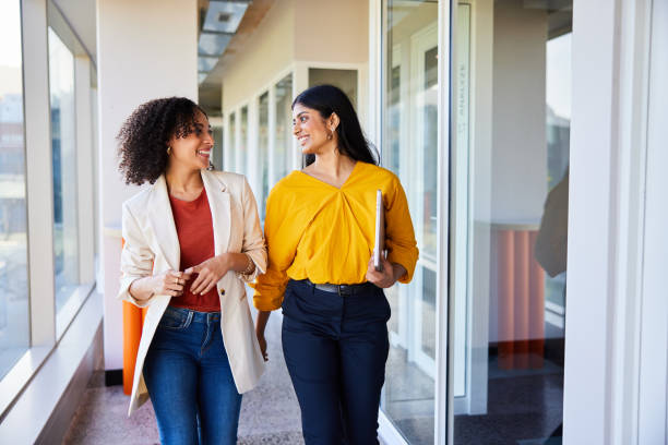 istock Diverse businesswomen talking and smiling while walking along an office corridor 1962648500