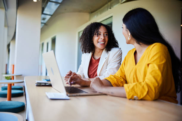 istock Two businesswomen smiling while working on a laptop at an office desk 1962652520