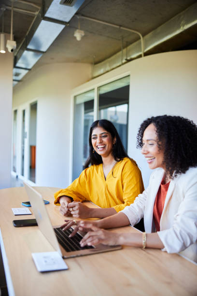 istock Diverse businesswomen laughing while working on a laptop in an office 1962655690