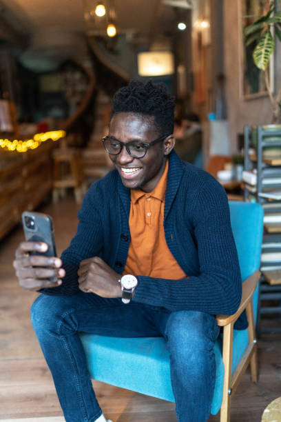 istock Cheerful black man using smart phone at coffee shop 1962663558