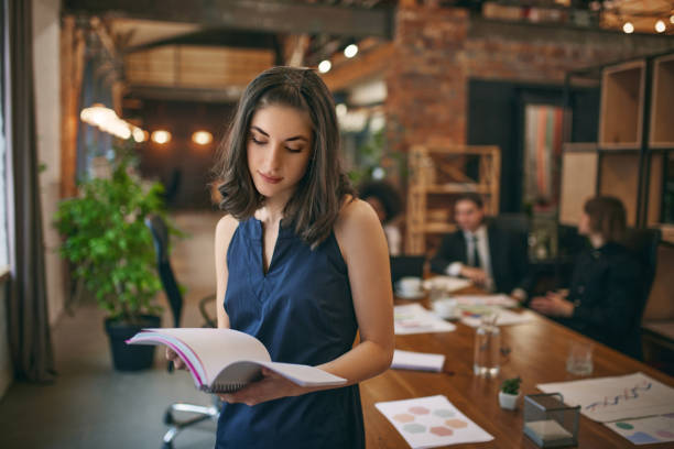 istock Focused student girl studying in public library for work on study research project, holding learning papers, notebook. 1962689587