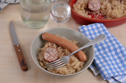 Sauerkraut plate with a frankfurter and a slice of morteau sausage with a fork and a glass of water