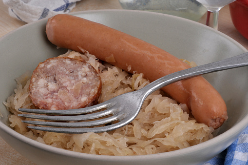 Sauerkraut plate with a frankfurter and a slice of morteau sausage with a fork close-up