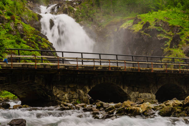 Norwegian landscape. Waterfall Latefoss Latefossen with stone arched bridge road, Odda Hordaland Norway. National tourist Hardanger road 13.