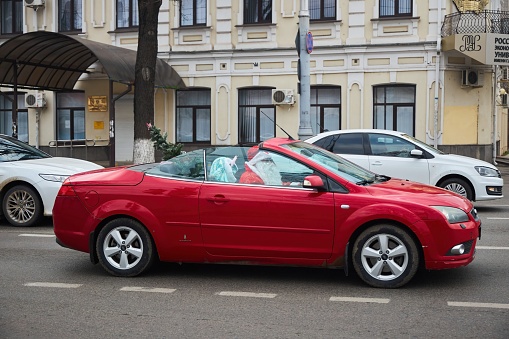 Krasnodar, Russia - December 31, 2022: Red convertible car with Santa Claus. City street