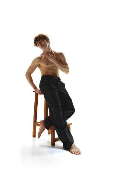 фотография размера тела привлекательного мужчины, позирующего сидящим на барном стуле на белом студийном фоне. полуобнаженный спортивный  - motion art naked studio shot стоковые фото и изображения