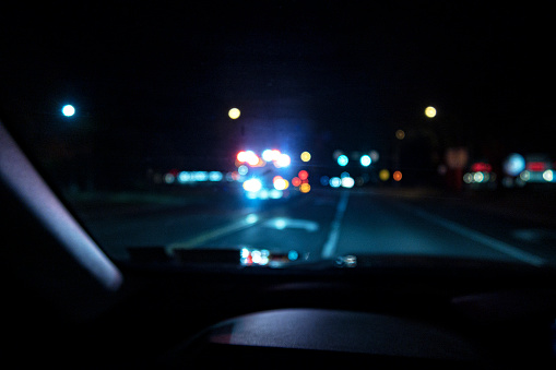 An abstract, defocused night time speeding emergency fire engine truck is approaching with all of its lights flashing and blinking to warn other vehicle traffic to get out of the way.