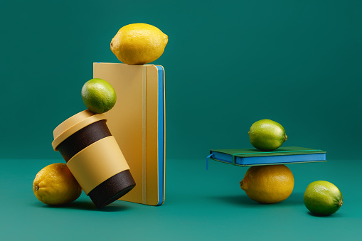 Reusable coffee cup with lid, yellow and green notebooks, lemon and lime on a green background. Balancing food